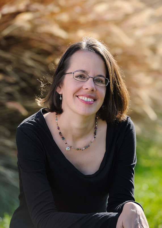 Woman with short brown hair, smiling, wearing glasses and a necklace Woman with short brown hair, smiling, wearing glasses and a necklace
